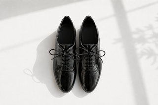A pair of black patent brogues oxford shoes