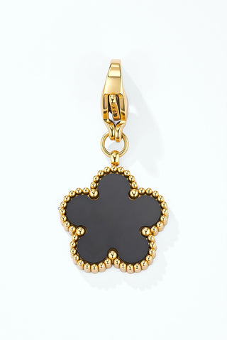 Gold-tone flower charm with a pale black enamel centre and a beaded edge, on a clip clasp